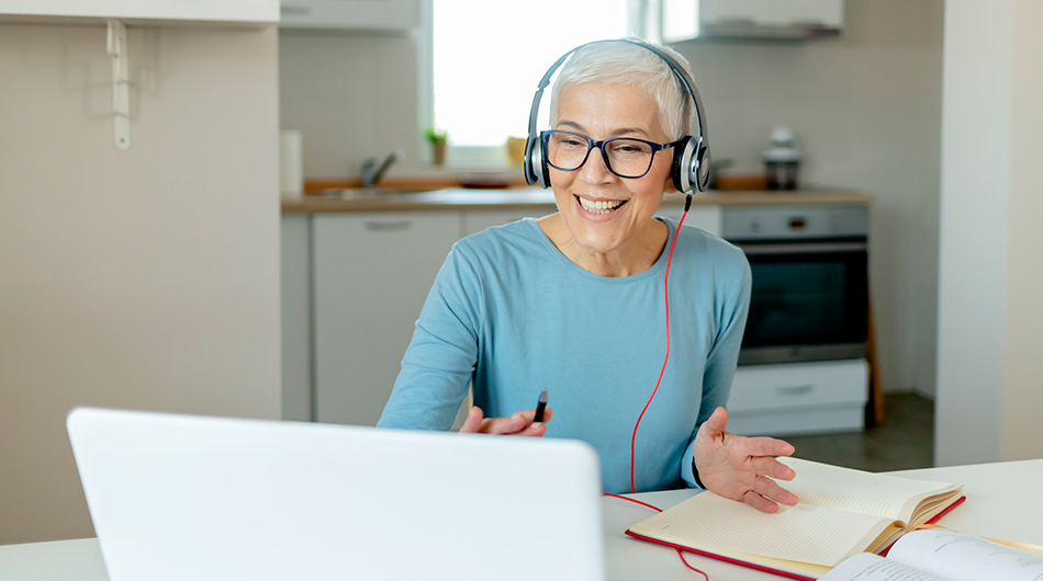 Zu sehen eine Frau mit Headset, die vor ihrem Laptop sitzt und in die Kamera spricht.