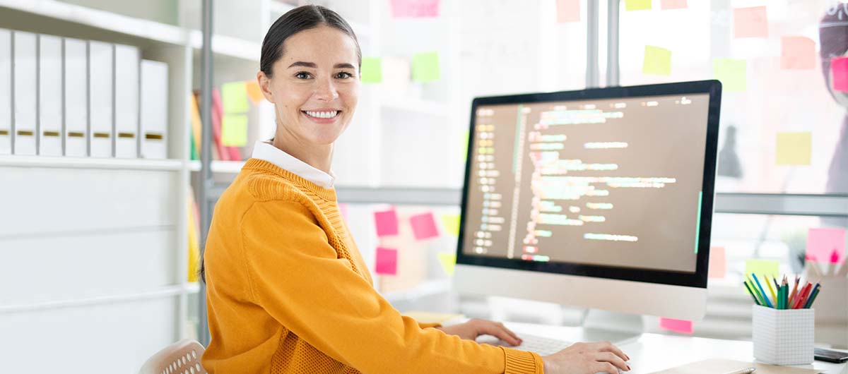 Eine Frau sitzt vor ihrem Computer und wird in ihrer Weiterbildung bereiten wir dich mit zentralem Methodenwissen und technischen Kenntnissen auf deinen Einstieg in die moderne Webentwicklung vor.