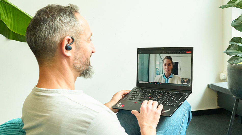 Zu sehen ist ein Coachee mit einem Laptop auf dem Schoß, auf dem Laptop ist eine Coachin zu sehen.